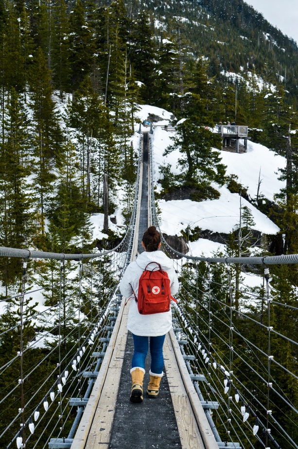 Girl with red backpack walking across bridge